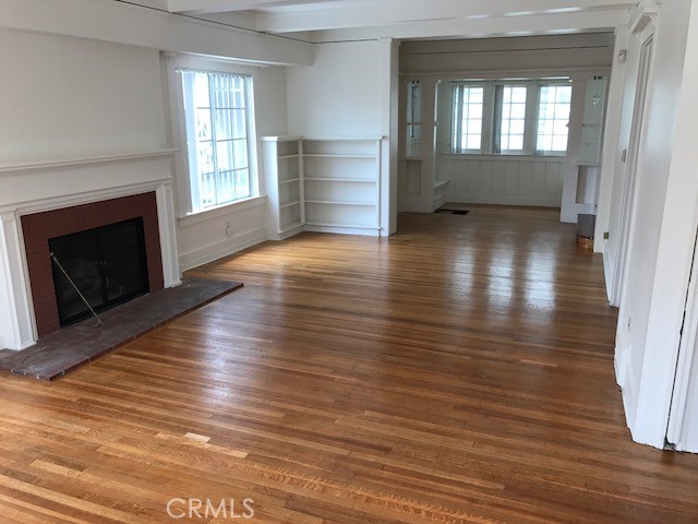 1624 South Gramercy Place Los Angeles, CA 90019 - Photo 3 of 20 an empty room with wooden floor fireplace and windows