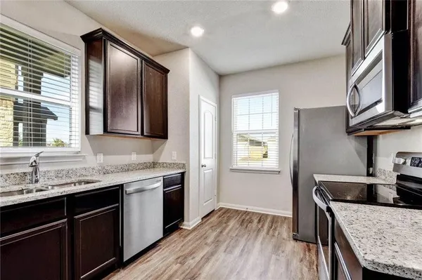 a kitchen with granite countertop stainless steel appliances a sink stove and cabinets