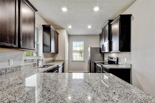 a kitchen with stainless steel appliances granite countertop a sink stove and refrigerator