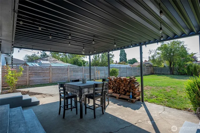 a view of patio with table and chairs under an umbrella with a barbeque