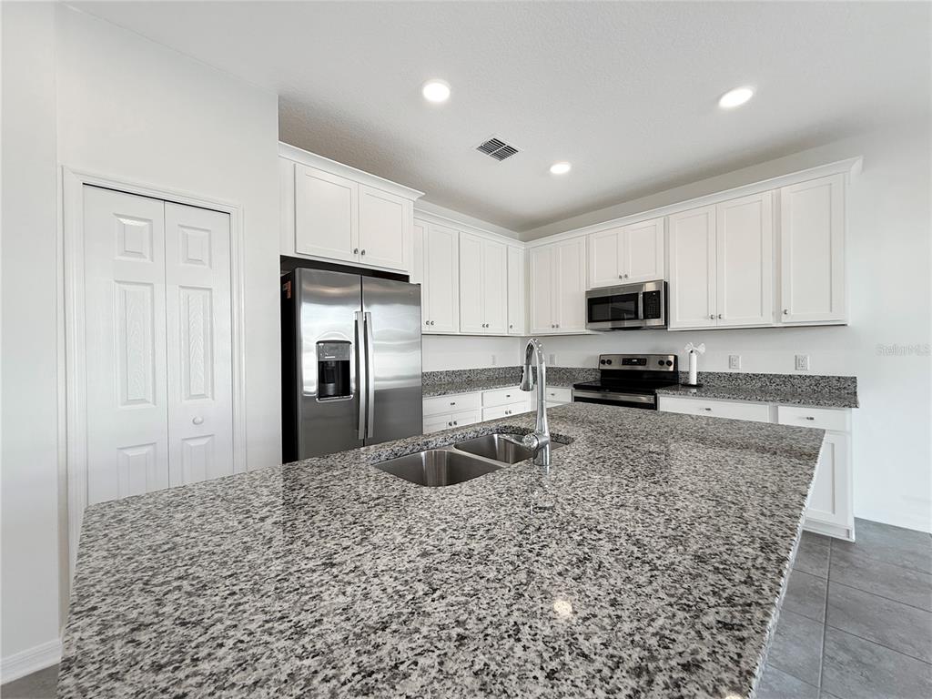 3023 Adams Cross Drive Zephyrhills, FL 33540 - Photo 18 of 36 a kitchen with granite countertop a refrigerator sink and cabinets