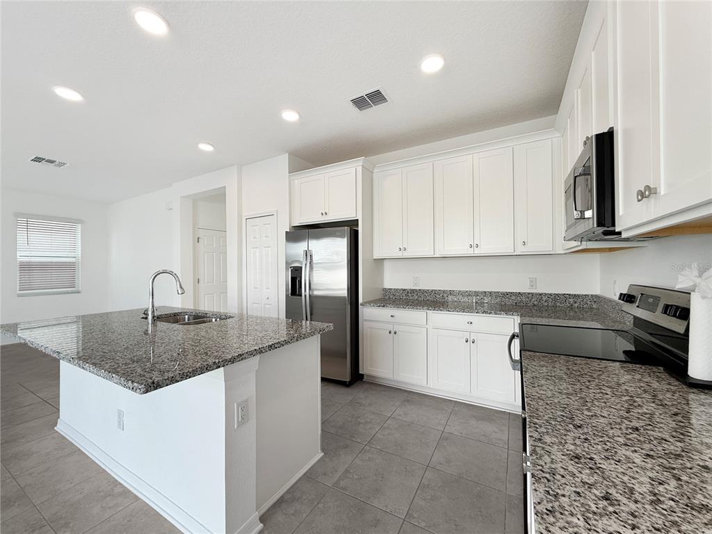 3023 Adams Cross Drive Zephyrhills, FL 33540 - Photo 5 of 36 a kitchen with stainless steel appliances granite countertop a sink stove and cabinets