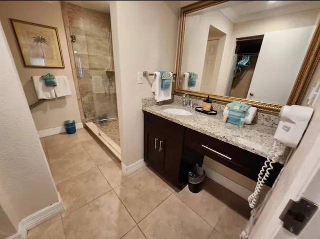 a spacious bathroom with a granite countertop sink a mirror a vanity and shower