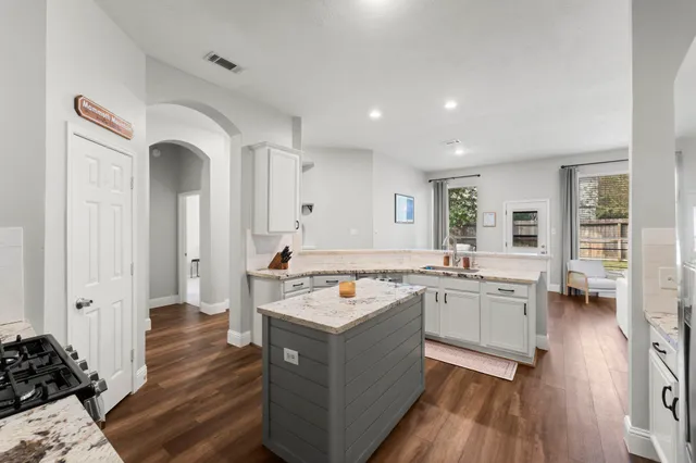 a living room with stainless steel appliances granite countertop furniture and a wooden floor