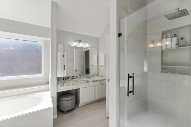 a spacious bathroom with a double vanity sink a mirror and a bathtub