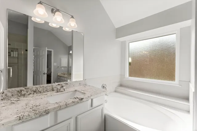 a bathroom with a granite countertop sink a large mirror and a bathtub with shower