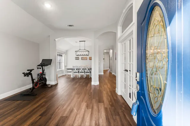 a view of a room with gym equipment and wooden floor