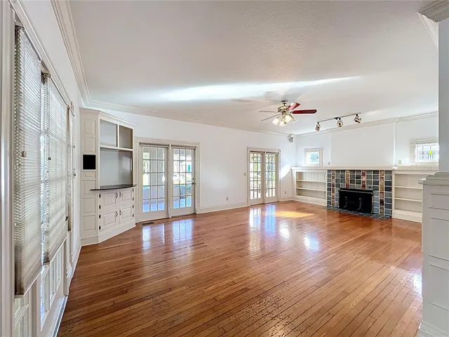 a view of an empty room with window and wooden floor