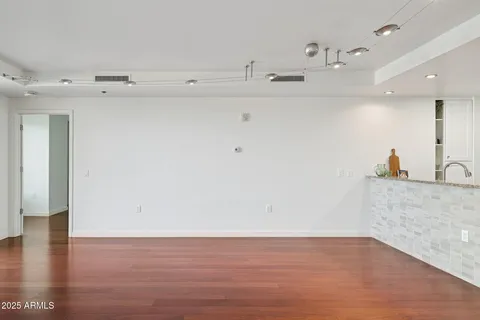 a view of an empty room with a window and wooden floor