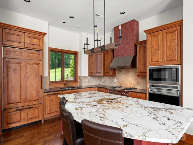 a kitchen with stainless steel appliances granite countertop a refrigerator and a stove top oven