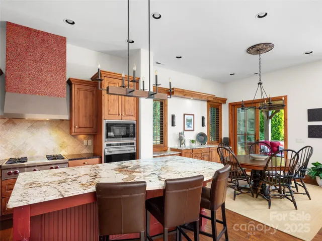 a kitchen with a stove a sink dishwasher a dining table and chairs with wooden floor