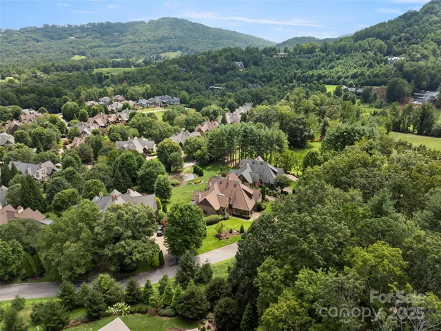 an aerial view of residential house with outdoor space and trees all around