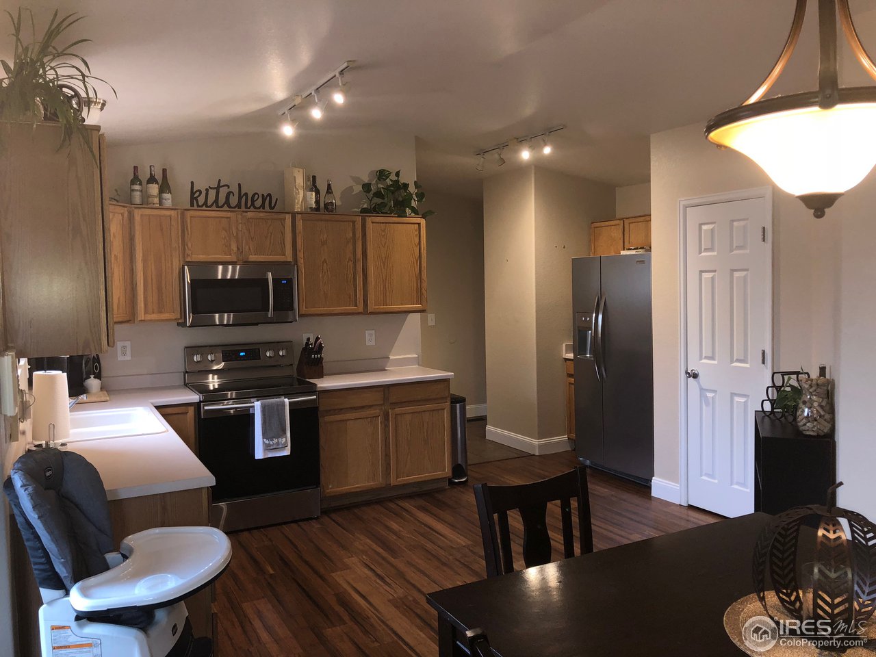 1282 Trail Ridge Road Longmont, CO 80504 - Photo 10 of 31 a kitchen with stainless steel appliances granite countertop a refrigerator a stove a sink dishwasher a dining table and chairs with wooden floor