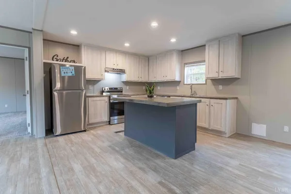 a kitchen with stainless steel appliances granite countertop a stove a sink a refrigerator and white cabinets with wooden floor