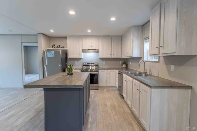 a kitchen with stainless steel appliances granite countertop wooden cabinets a sink and dishwasher a stove top oven with wooden floor