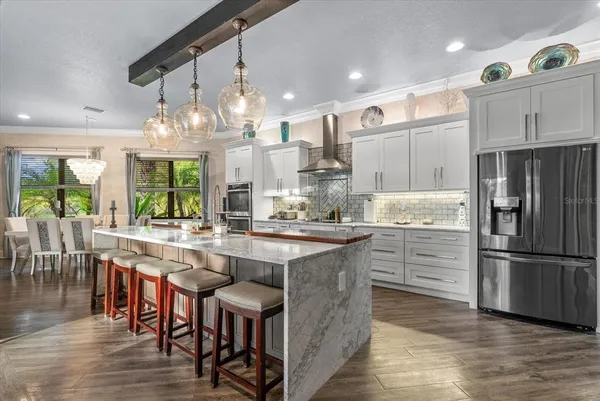 a kitchen with stainless steel appliances granite countertop a table chairs and a refrigerator