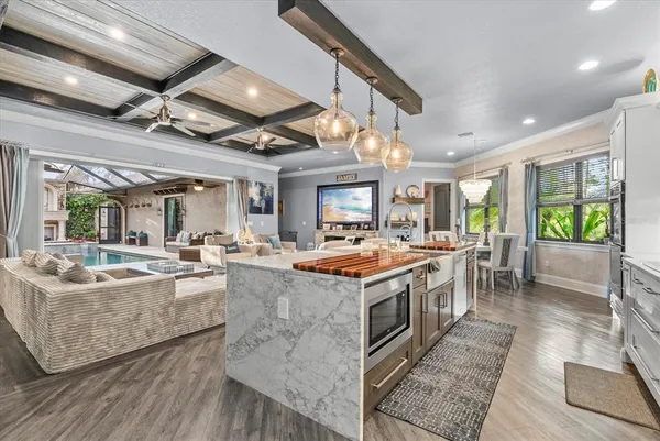 a large kitchen with kitchen island a stove a sink a dining table and chairs with wooden floor