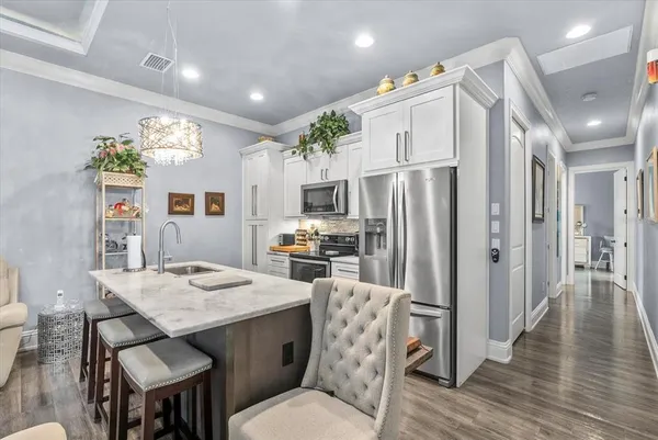 a kitchen with stainless steel appliances a dining table chairs and refrigerator