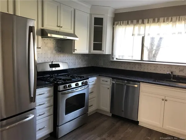 a kitchen with stainless steel appliances granite countertop white cabinets and a stove