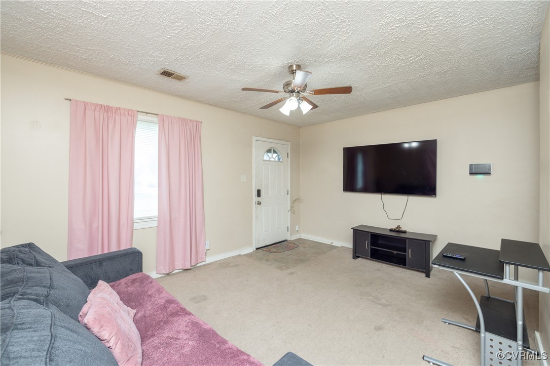 Carpeted living room featuring a ceiling fan