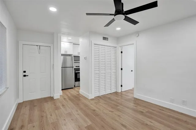 a view of empty room with wooden floor and ceiling fan