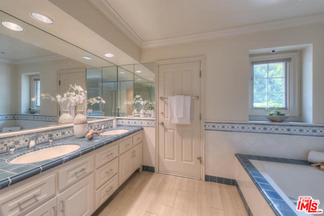 791 North Bundy Drive Los Angeles, CA 90049 - Photo 23 of 33 a bathroom with a double vanity sink a mirror and a shower