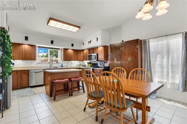 a kitchen with stainless steel appliances kitchen island granite countertop a table chairs and a refrigerator