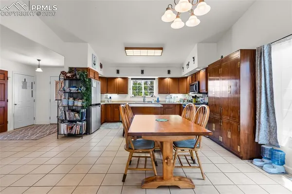 a kitchen with stainless steel appliances granite countertop a stove a refrigerator a oven a dining table and chairs with wooden floor