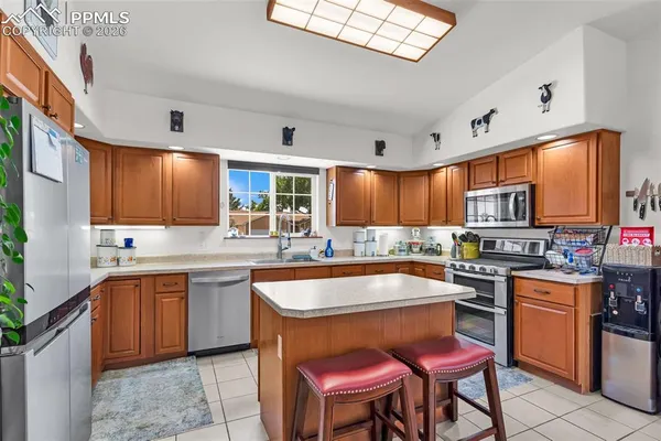 a kitchen with stainless steel appliances granite countertop wooden cabinets a sink a stove a dining table and chairs