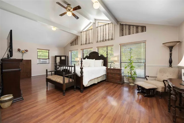 a spacious bedroom with a bed wooden floor and a large window