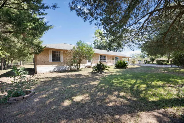 a front view of a house with garden and trees
