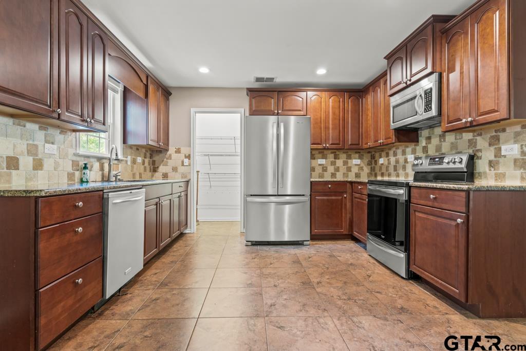 228 Cambridge Lane Longview, TX 75601 - Photo 7 of 26 a kitchen with stainless steel appliances granite countertop a stove top oven a sink dishwasher a refrigerator and cabinets with wooden floor