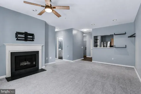 a view of an empty room with chandelier fan and fire place