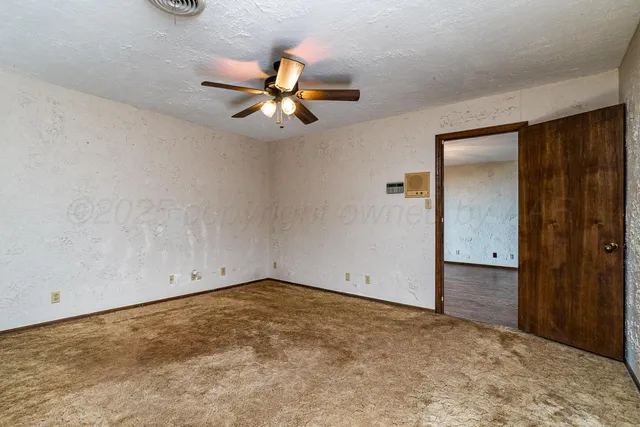 an empty room with a ceiling fan and a window