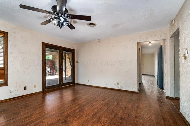 a view of an empty room with wooden floor and a window