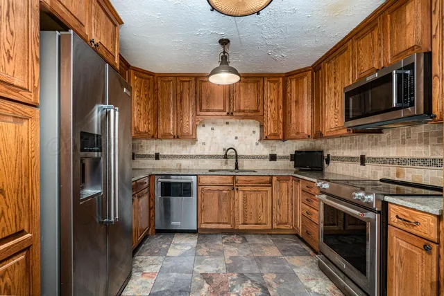 a kitchen with stainless steel appliances granite countertop a stove sink microwave and refrigerator