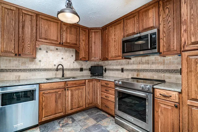 a kitchen with stainless steel appliances granite countertop a stove microwave and sink