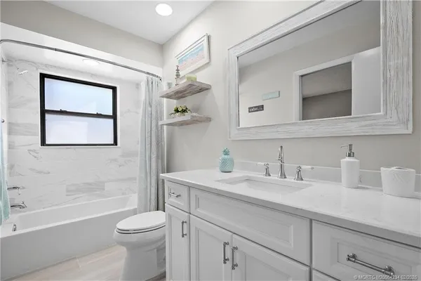 a bathroom with a toilet a sink a tub and mirror