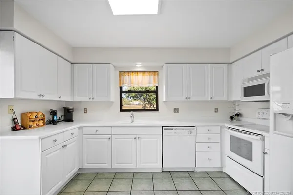a kitchen with white cabinets appliances and a window