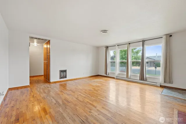 a view of an empty room with wooden floor and a window
