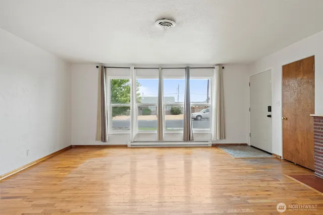 a view of an empty room with a window and fireplace