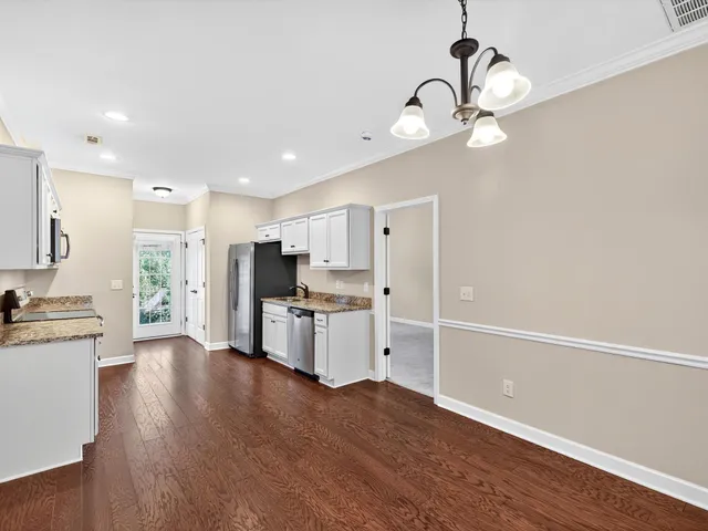 a large kitchen with kitchen island a stove a sink a refrigerator and a wooden floor