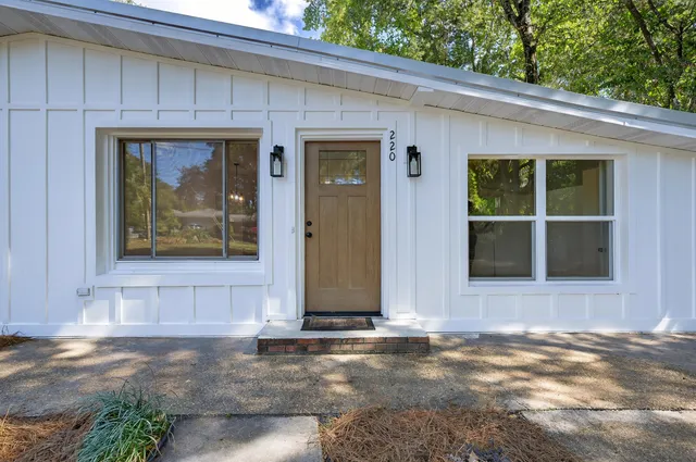 a view of an empty room with wooden floor fireplace and a window