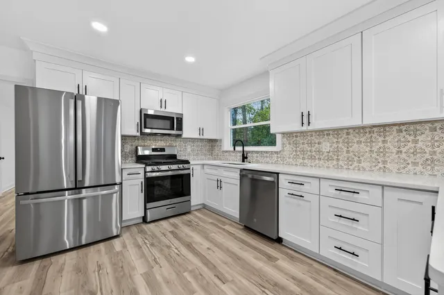 a kitchen with granite countertop a refrigerator and a stove top oven