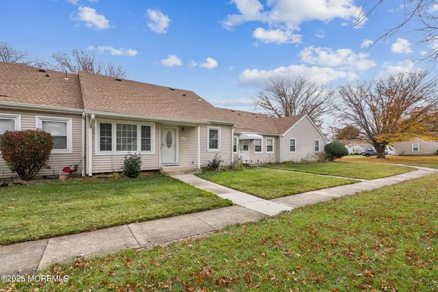 a view of a house with a big yard and large tree