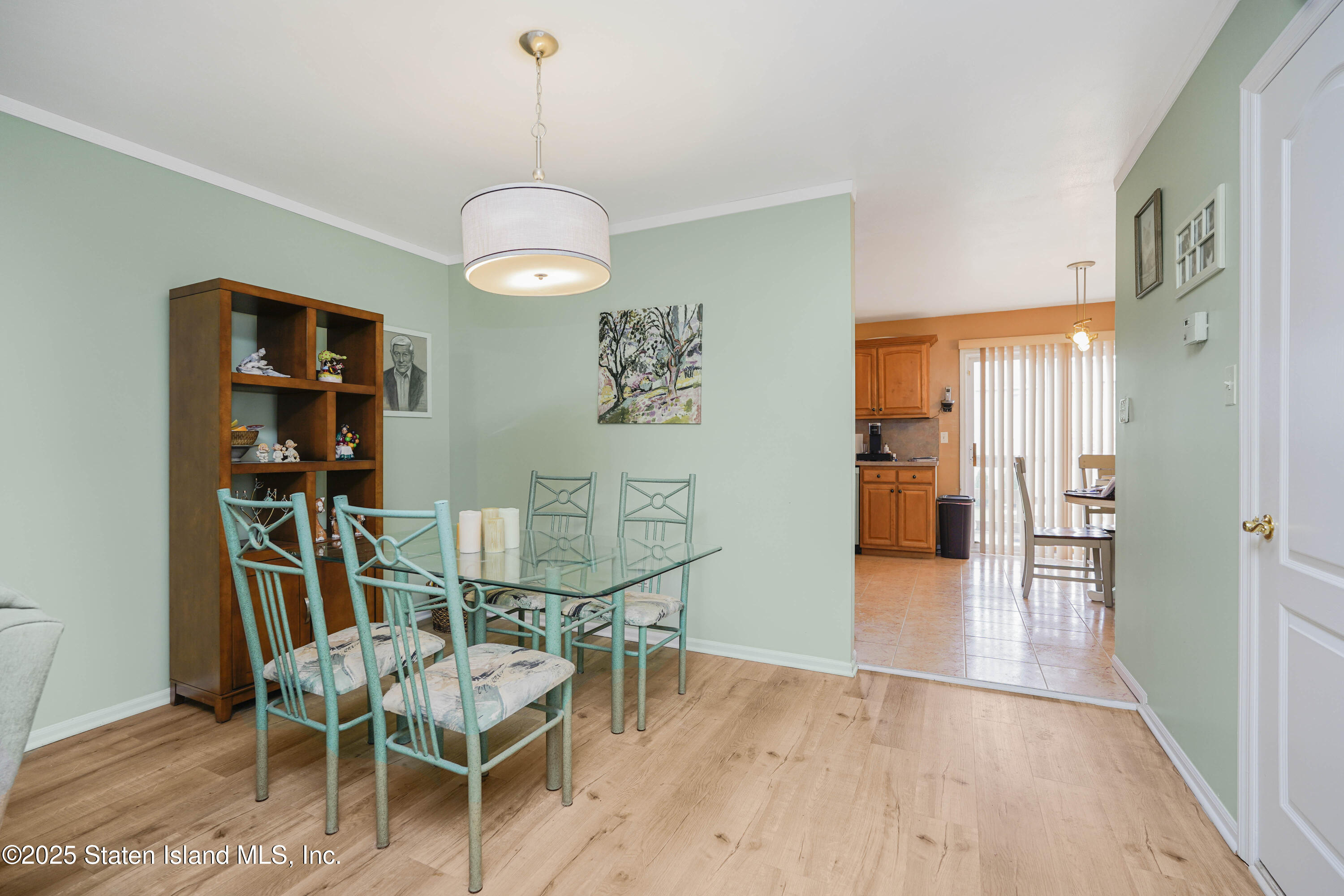 119 Glenn Road Staten Island, NY 10314 - Photo 3 of 26 a dining room with wooden floor a chandelier a glass table and chairs