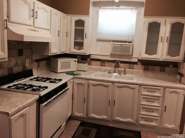 a kitchen with granite countertop a sink stove and cabinets