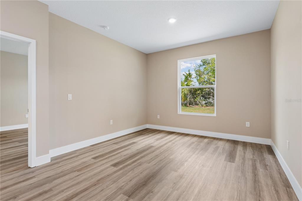 21 Postman Lane Palm Coast, FL 32164 - Photo 7 of 13 an empty room with wooden floor and windows