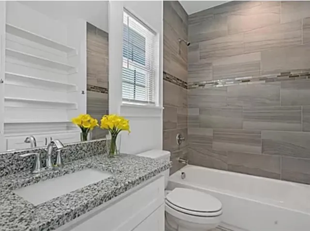 a bathroom with a granite countertop sink a toilet and bathtub