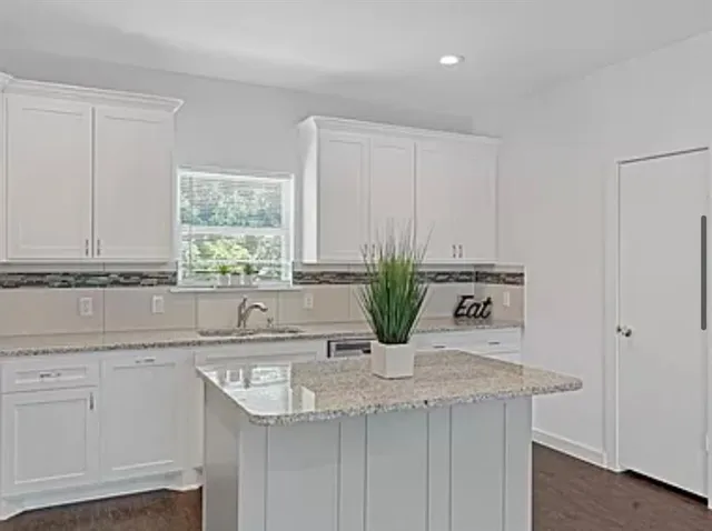 a kitchen with granite countertop a sink and white cabinets